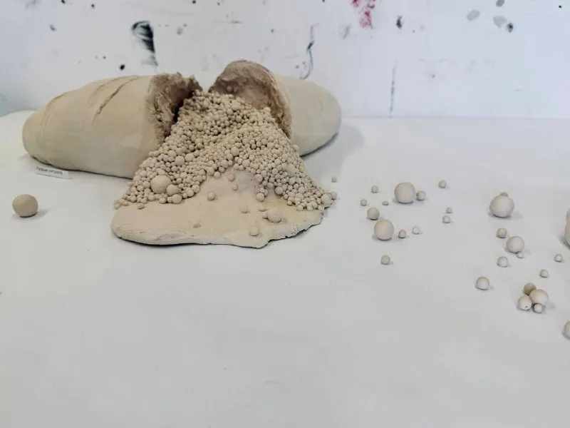 Керамическая скульптура: разломленный батон хлеба, из которого высыпаются глиняные шарики.