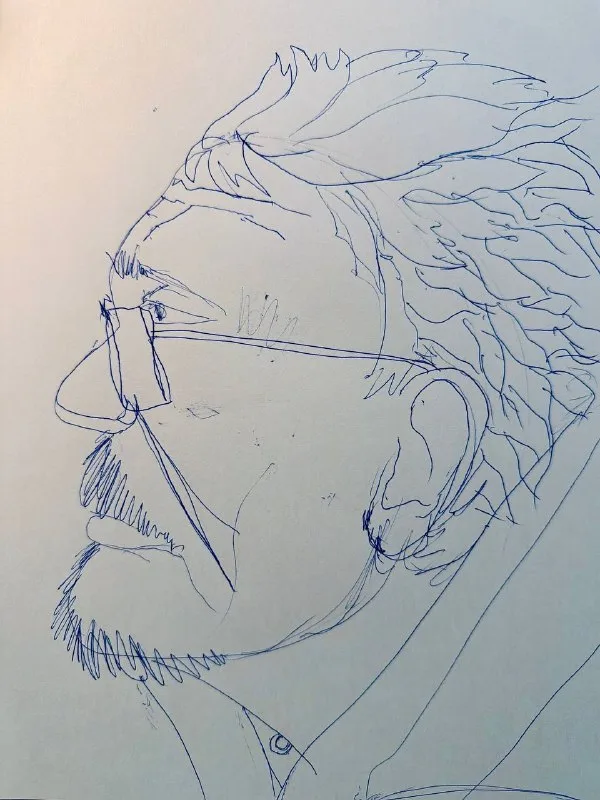 Набросок синей ручкой: профиль мужчины в очках и с бородой.