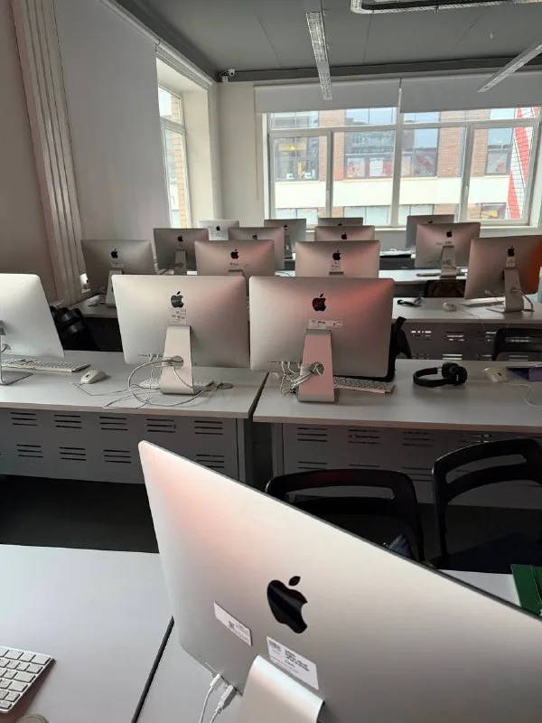Компьютерный класс с рядами моноблоков Apple iMac на столах.