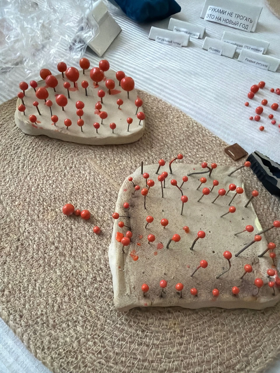 Красные керамические икринки на проволочных ножках, закрепленные в глиняных подставках.
